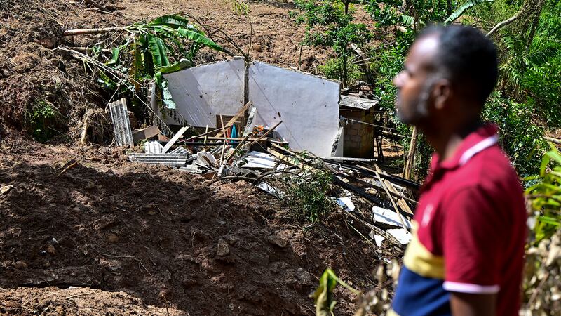 A man walks past a shattered house following landslides in the aftermath of Cyclone Ditwah in Hadabima village near Sarasavigama.